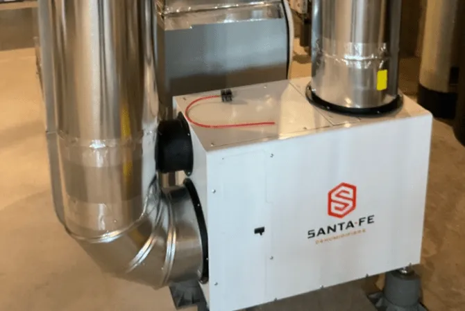 A whole-home dehumidifier connected to metal ductwork in a basement